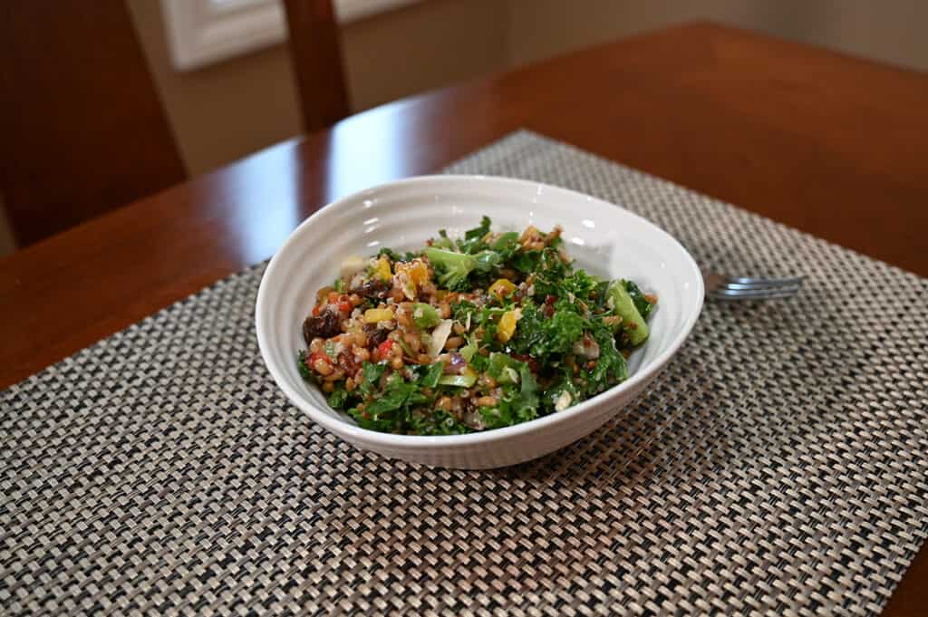 Side view image of the salad served in a white bowl with a fork resting beside it.