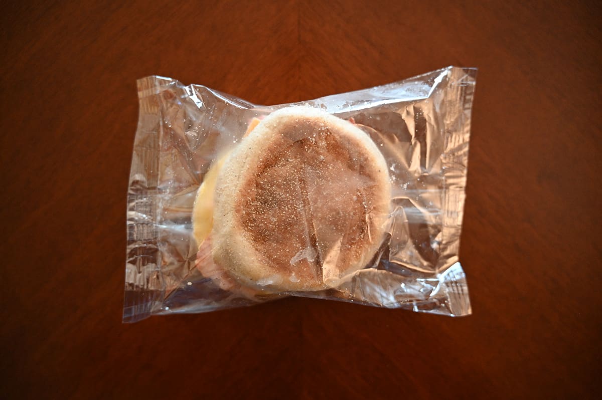 Top down image of one breakfast sandwich in it's wrapper sitting on a dining table.