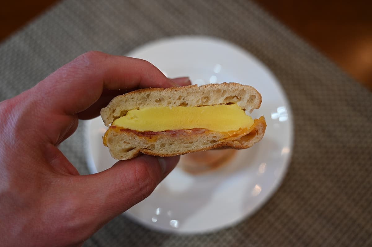Closeup image of a breakfast sandwich with a bite taken out of it showing the inside.
