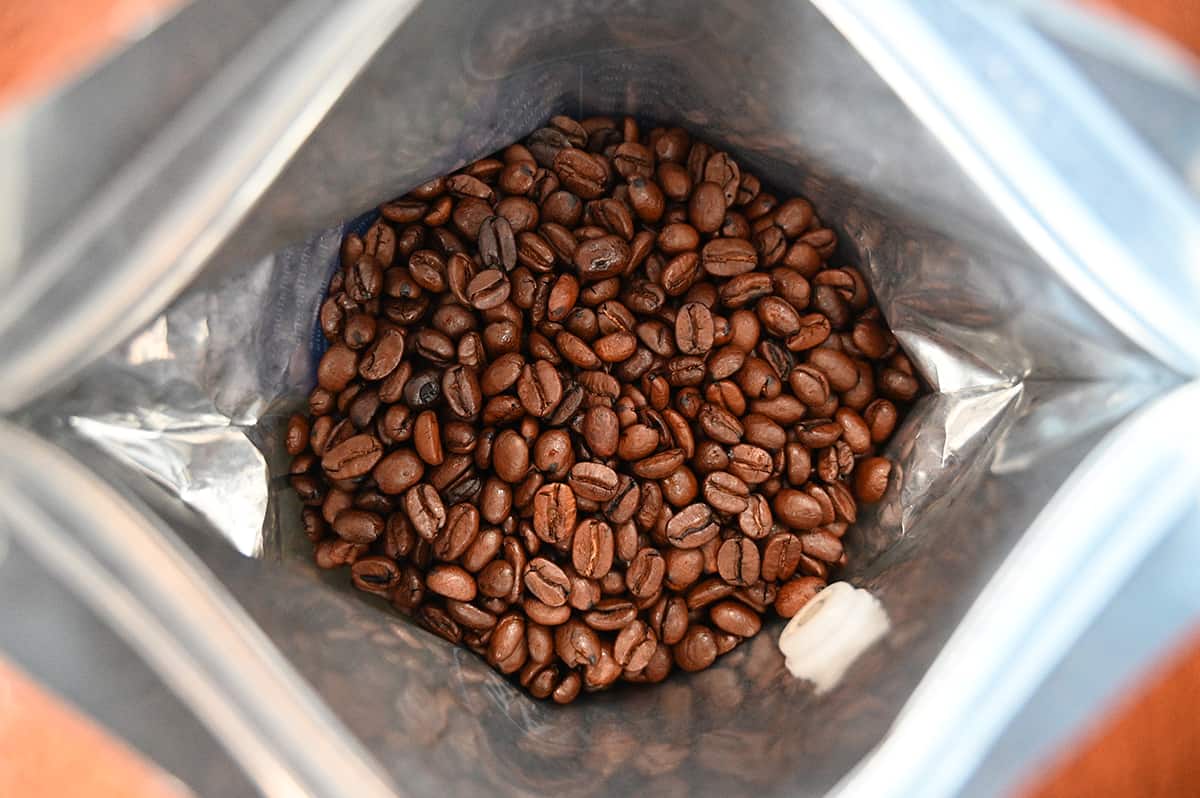 Top down image of the bag of coffee beans open so you can see the whole beans inside the bag,
