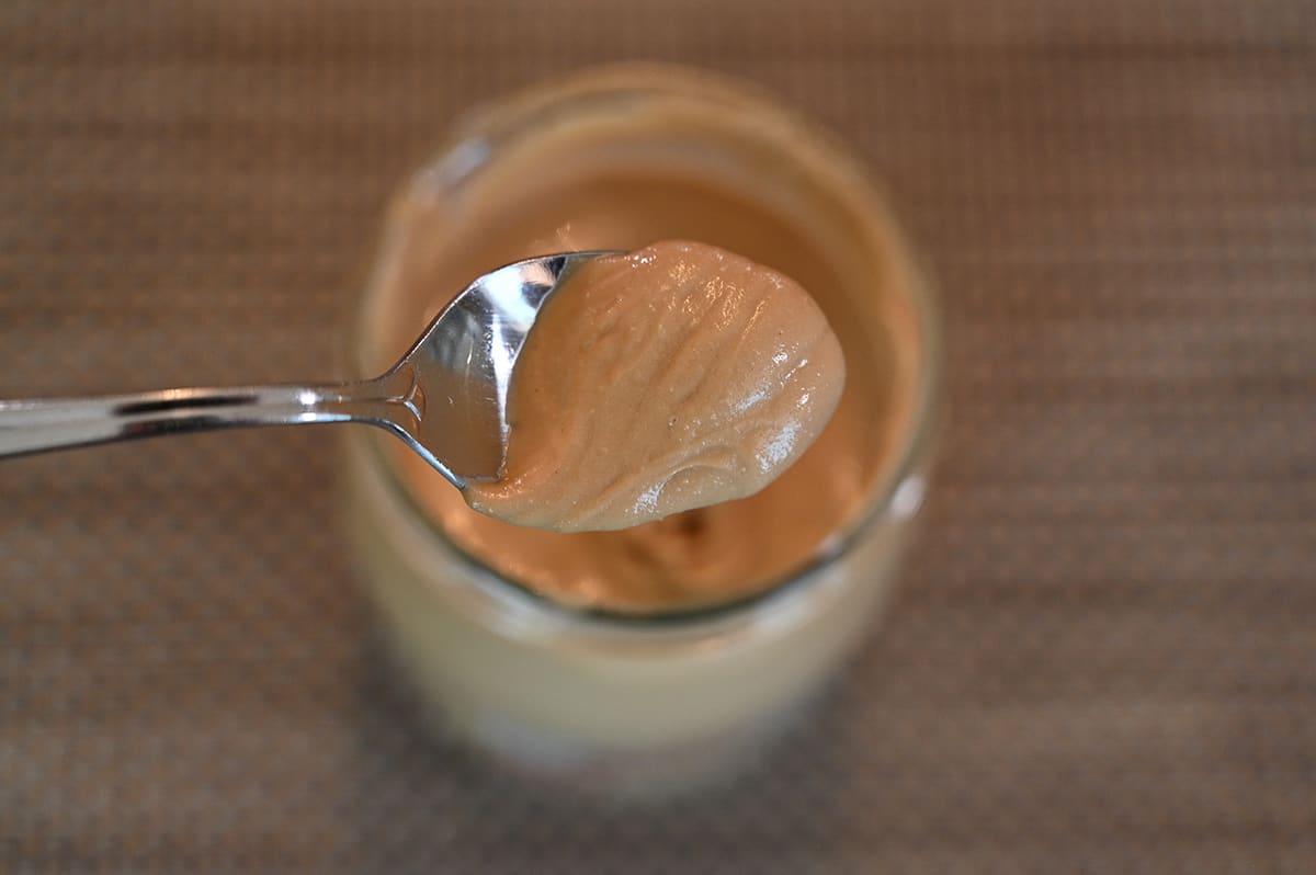 Top down image of spoonful of almond cream over top the opened jar.