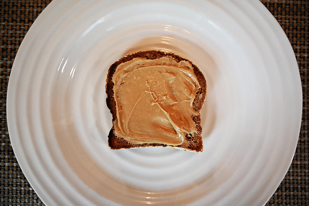 Top down image of the almond cream spread on a piece of toast on a white plate.