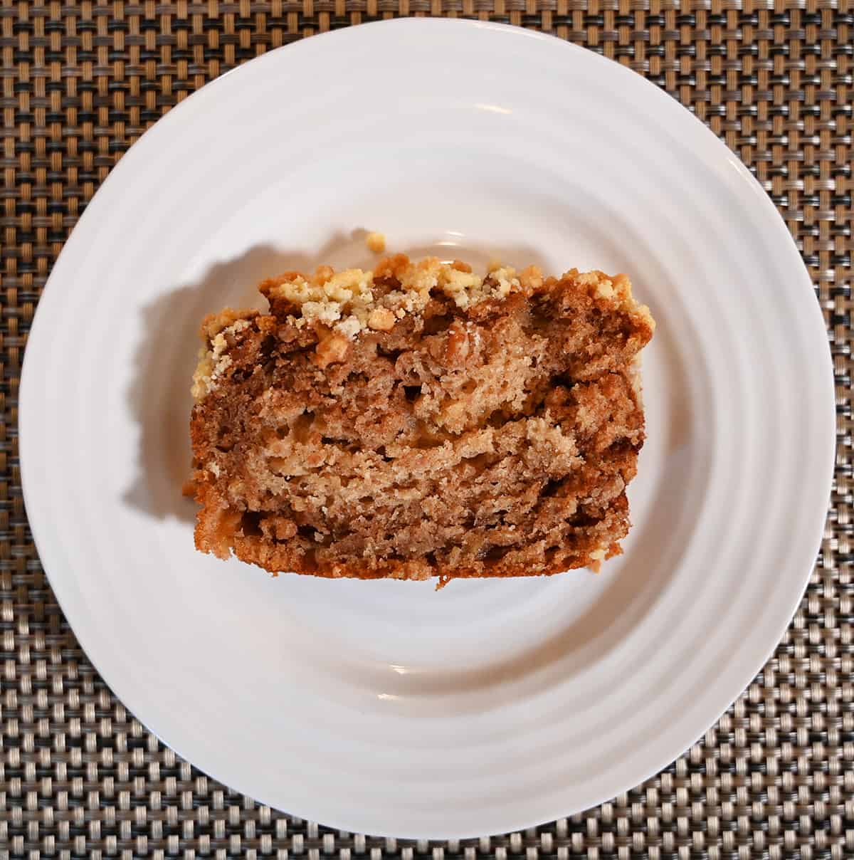 Top down image of  a slice of apple fritter loaf cake served on a white plate.