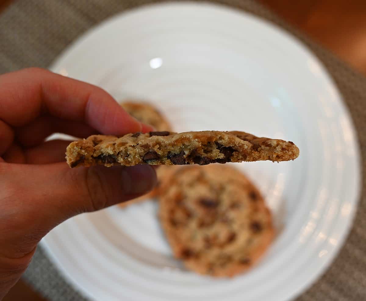 Closeup image of a hand holding one cookie with a bite taken out of it so you can see what the center of the cookie looks like.