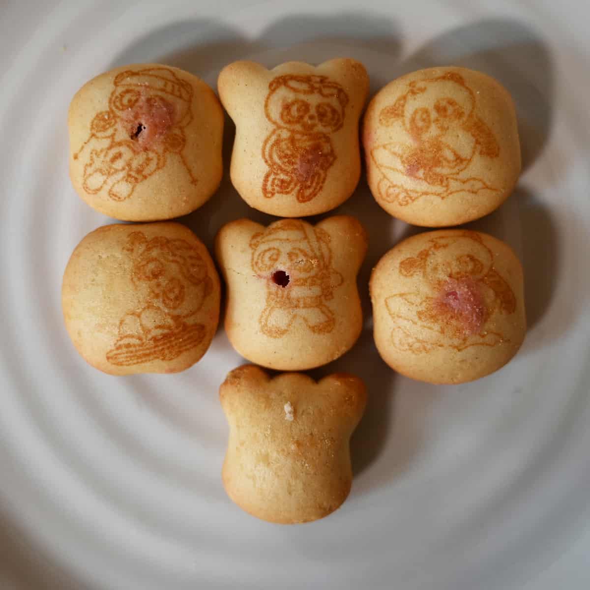 Top down image of seven Hello Panda Cookies served on a plate. Each cookie has an image of a panda doing a different activity on it.