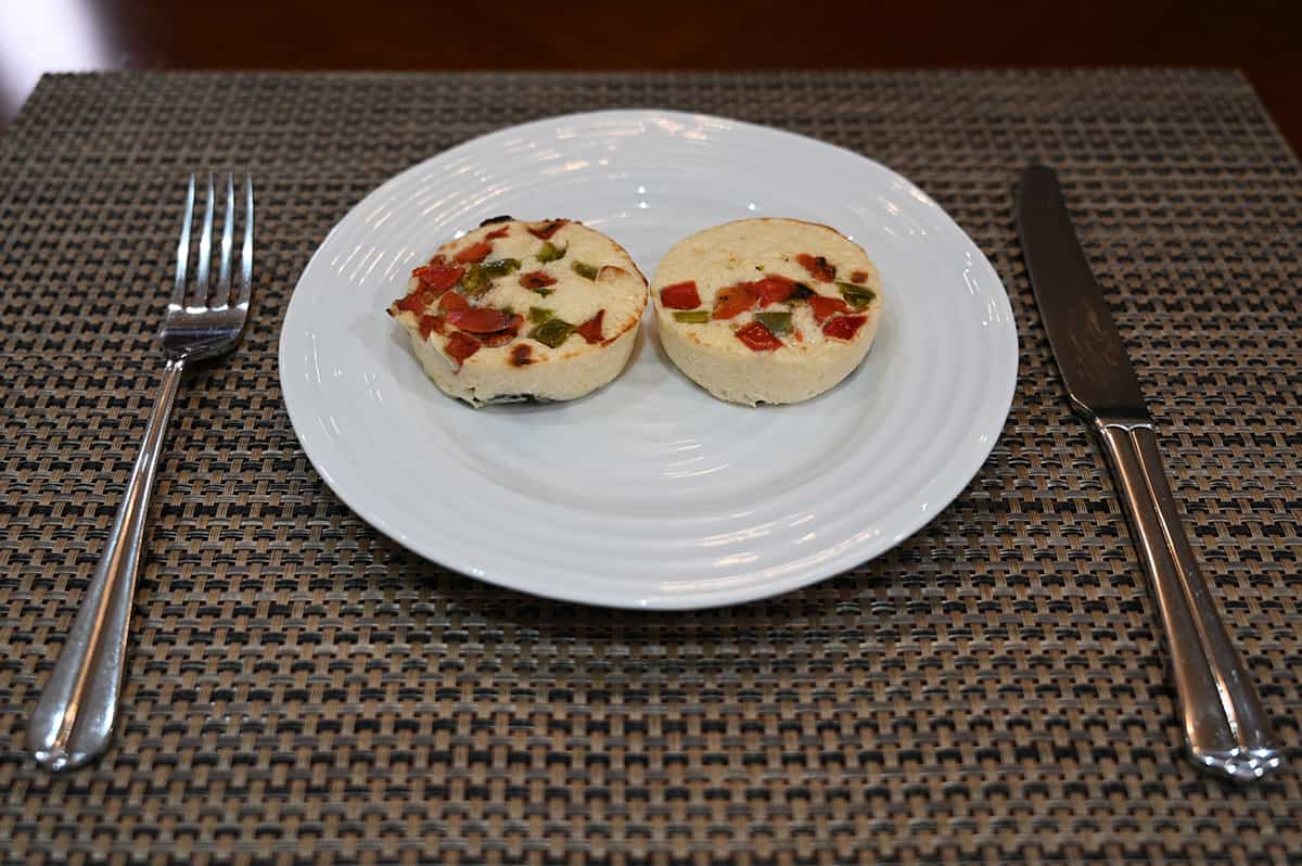 Side view image of two cooked spinach & bell pepper egg bites sitting on a plate.