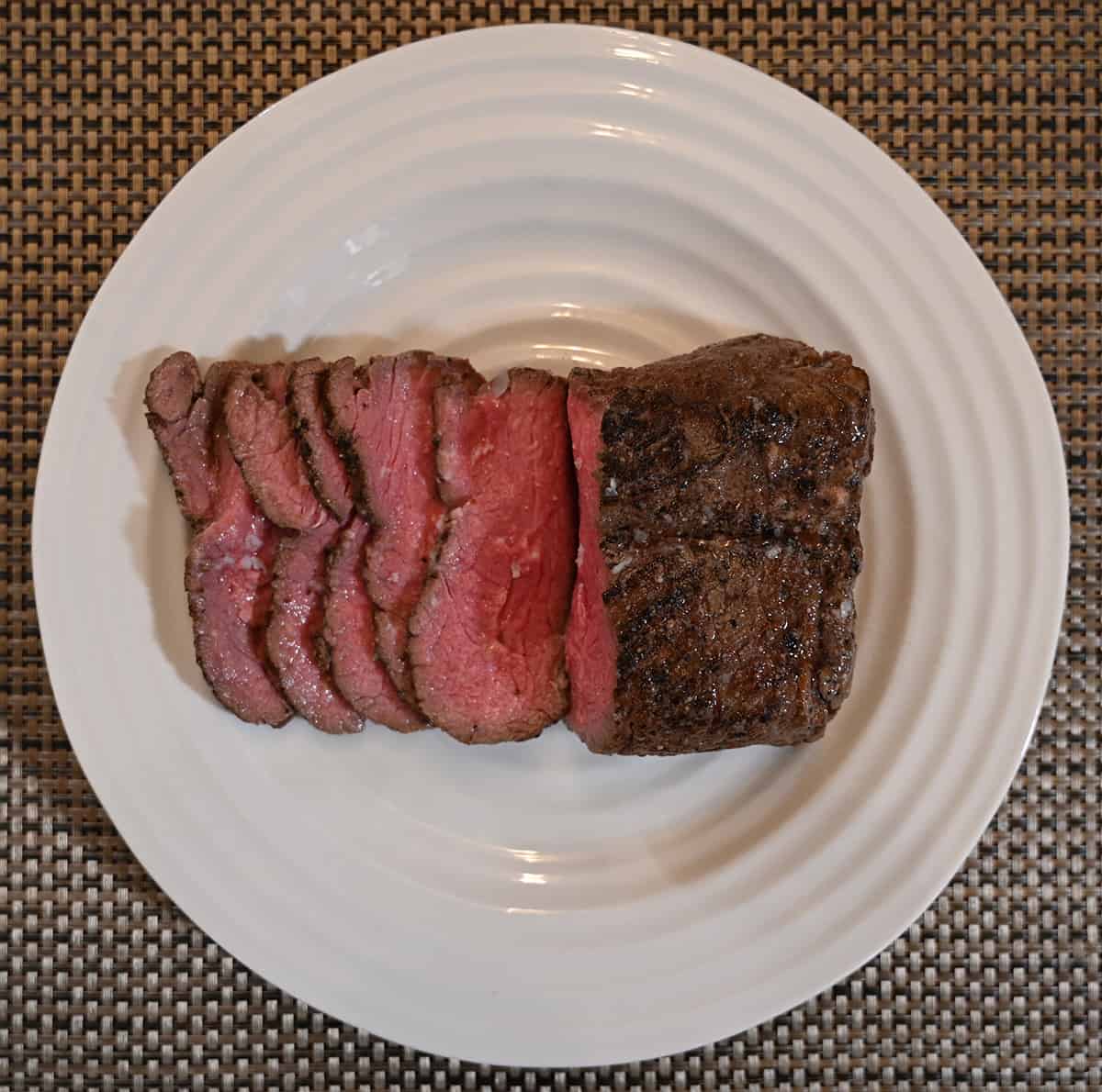 Image of a plate of sliced sirloin served cold right from the package. The sirloin appears rare. 