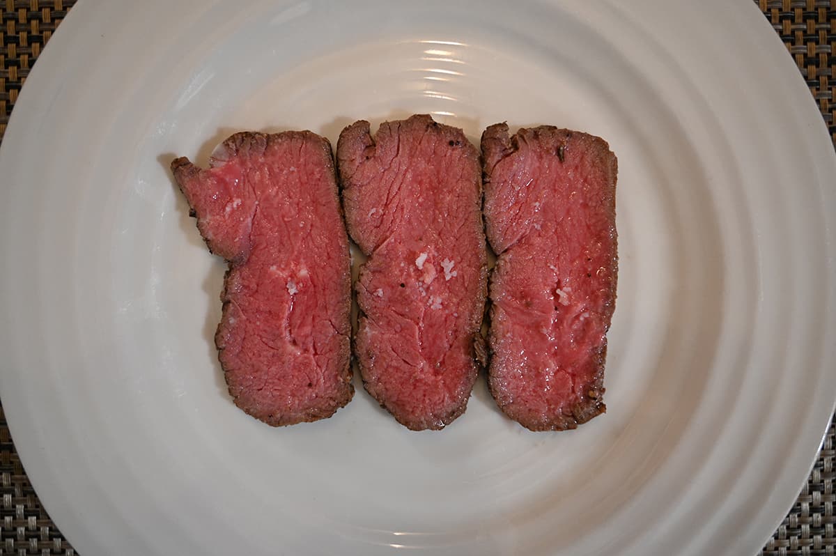 Top dwn image of three slices of sirloin, served on a white plate. The sirloin appears rare.
