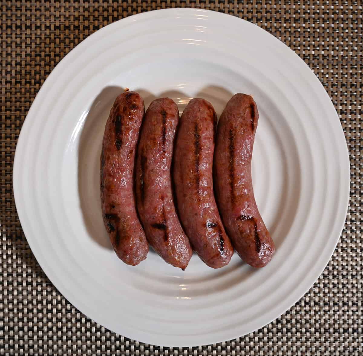 Image of four cooked bratwurst served on a white plate.
