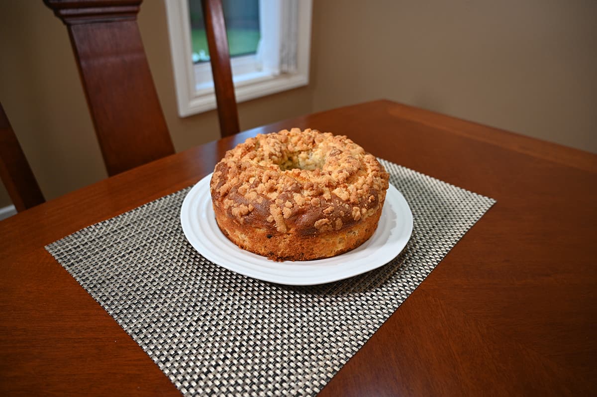 Image of the coffee cake unwrapped and served on a white plate. The plate is sitting on a dining room table.