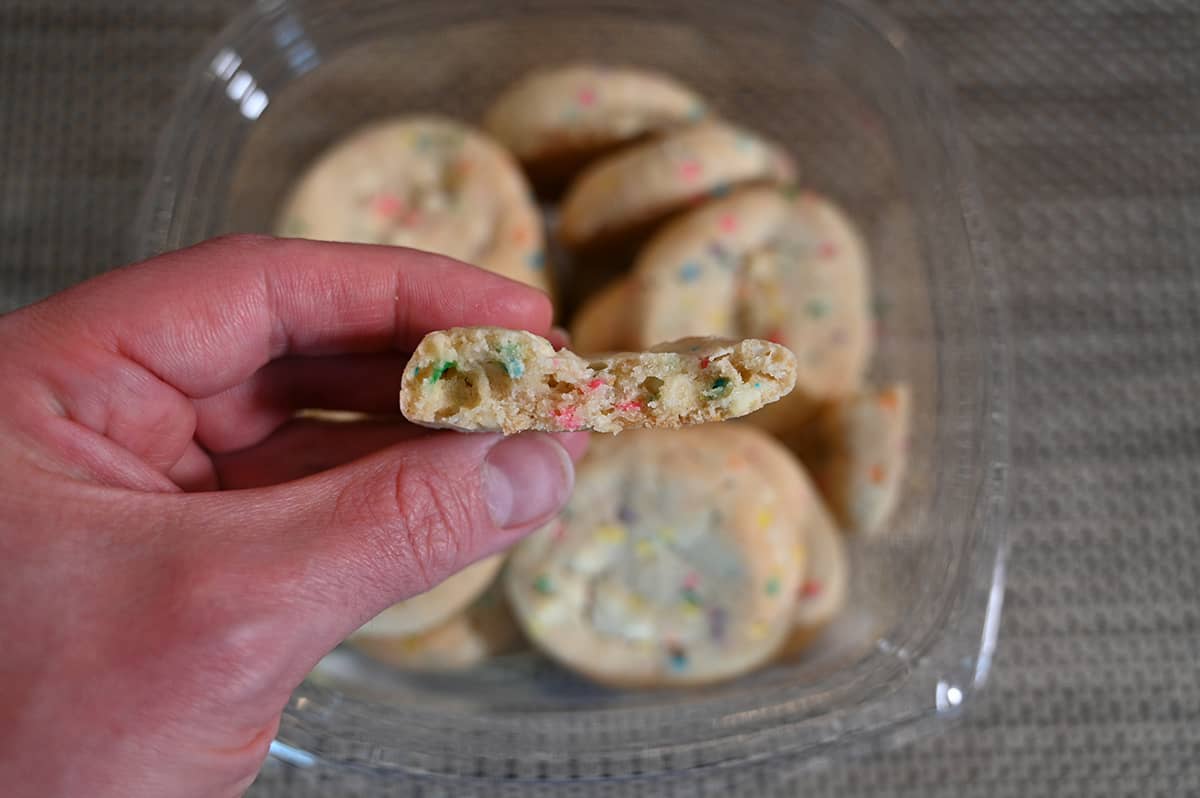 Closeup image of a hand holding a cookie with a bite taken out of it so you can see the center of the cookie.