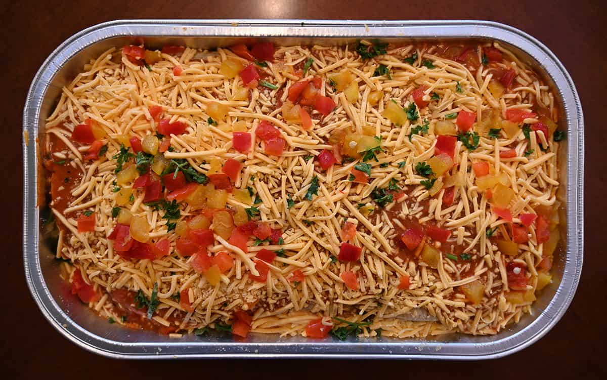 Top down image of the Costco Kirkland Signature Enchilada Bake tray sitting on a table opened so you can see the ingredients.