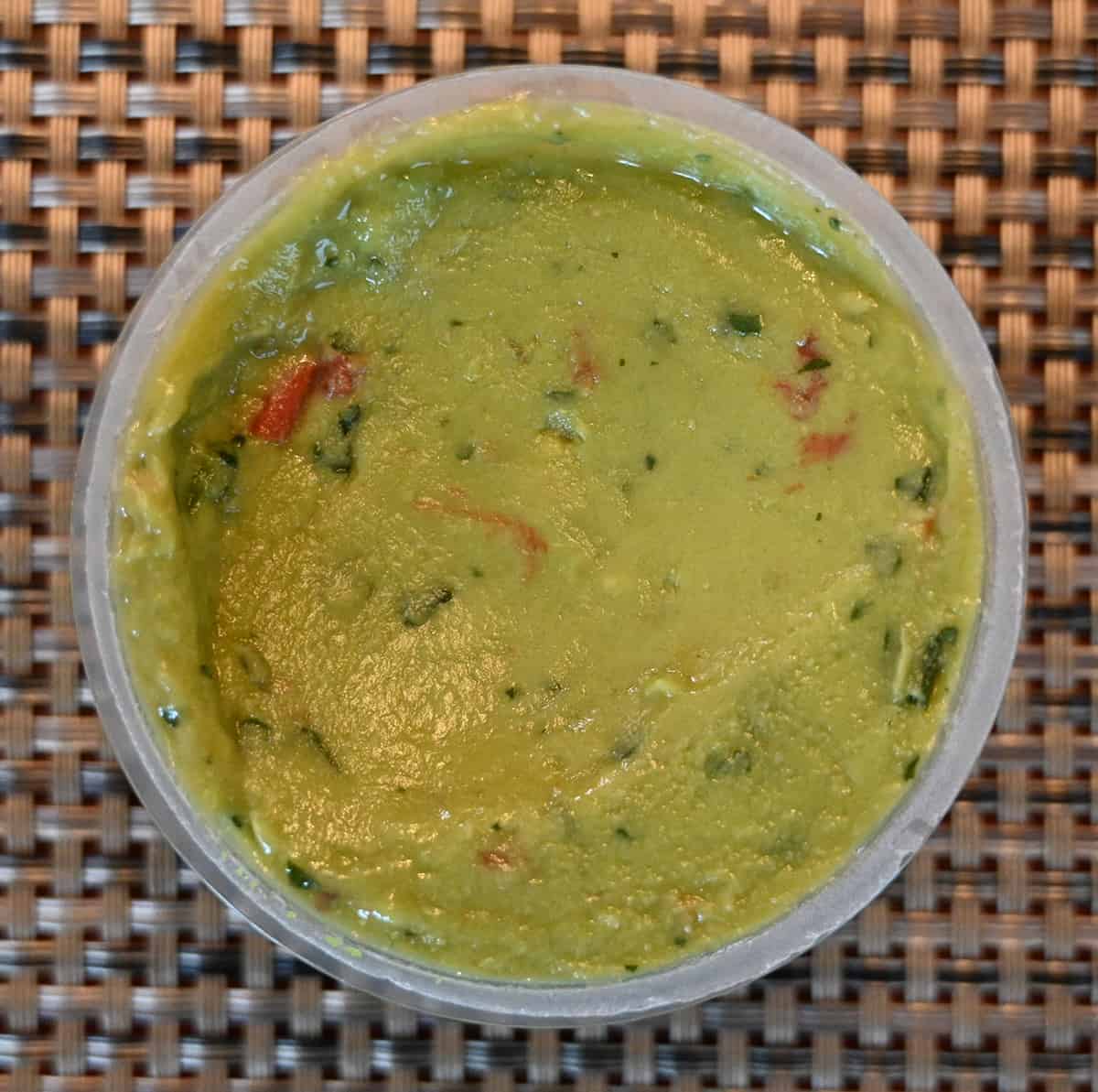 Top down closeup image of one open guacamole cup showing what the guacamole looks like.