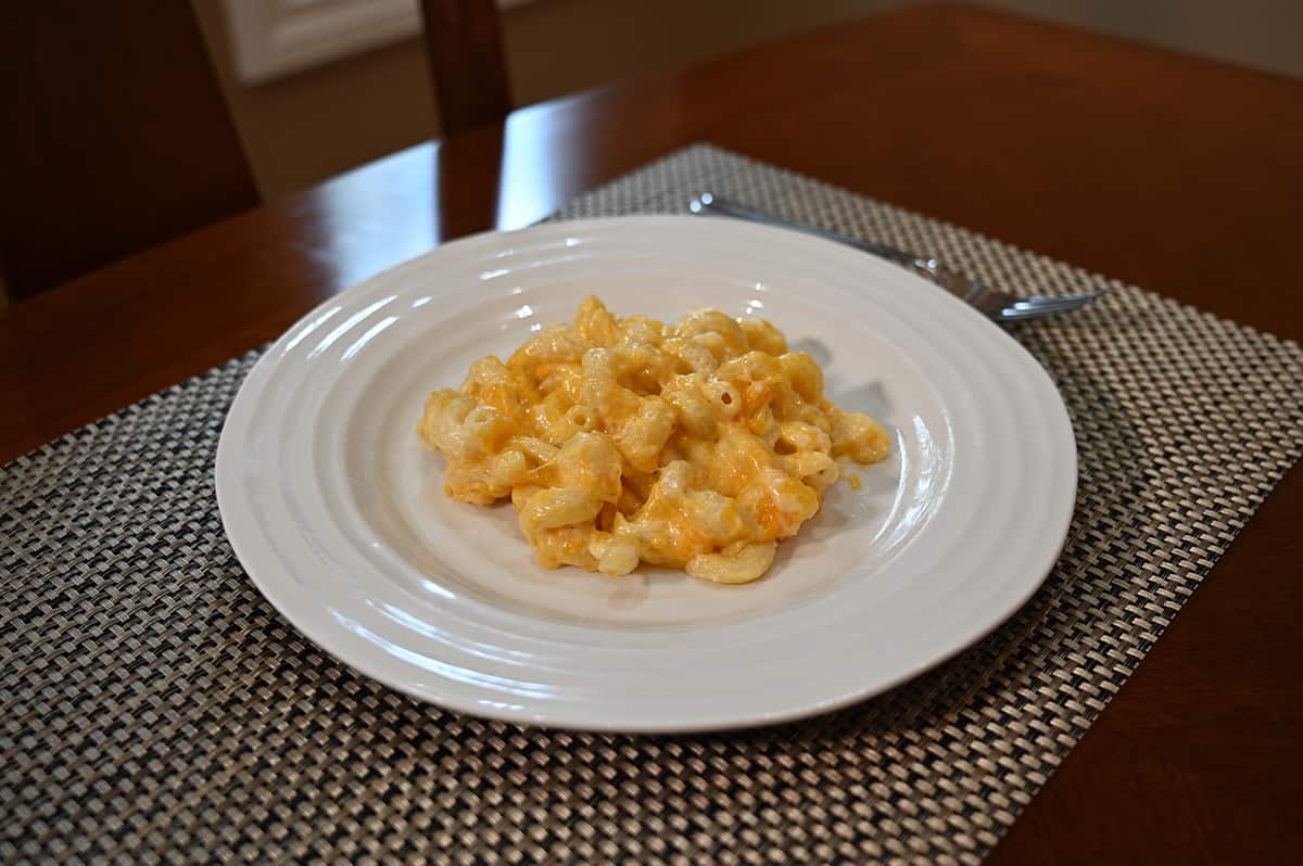 Side view image of  the mac and cheese served on a white plate there is an abundance of cheese on the macaroni.