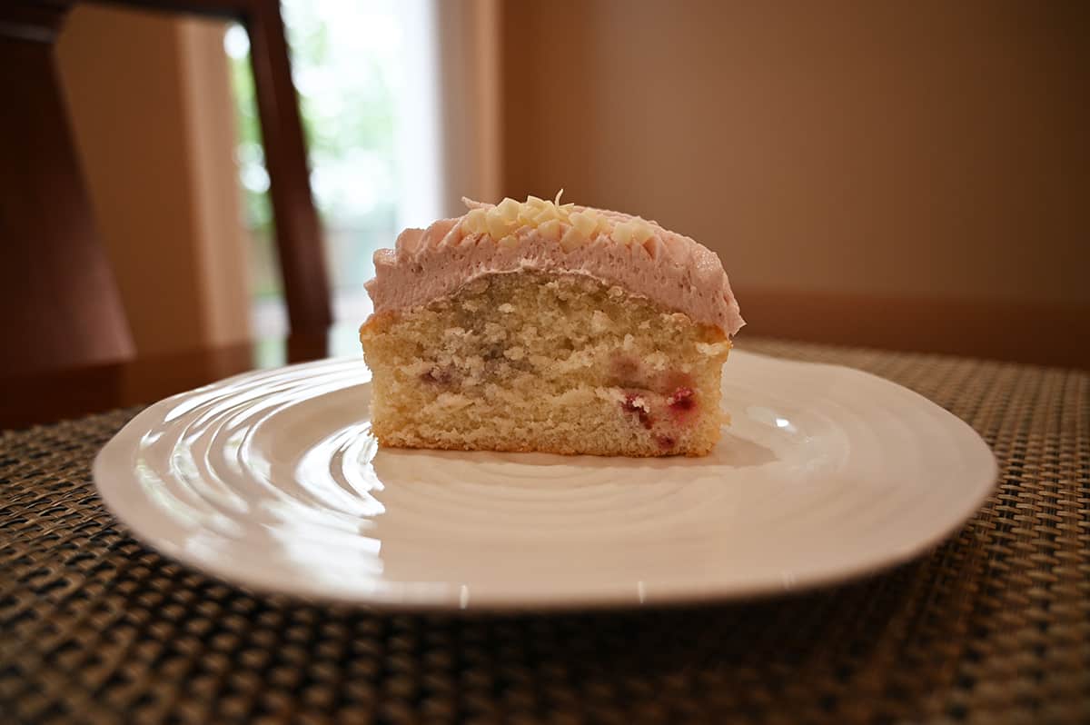 Image of a mini cake cut in half and served on a white plate so the lack of raspberries in the cake is apparent.