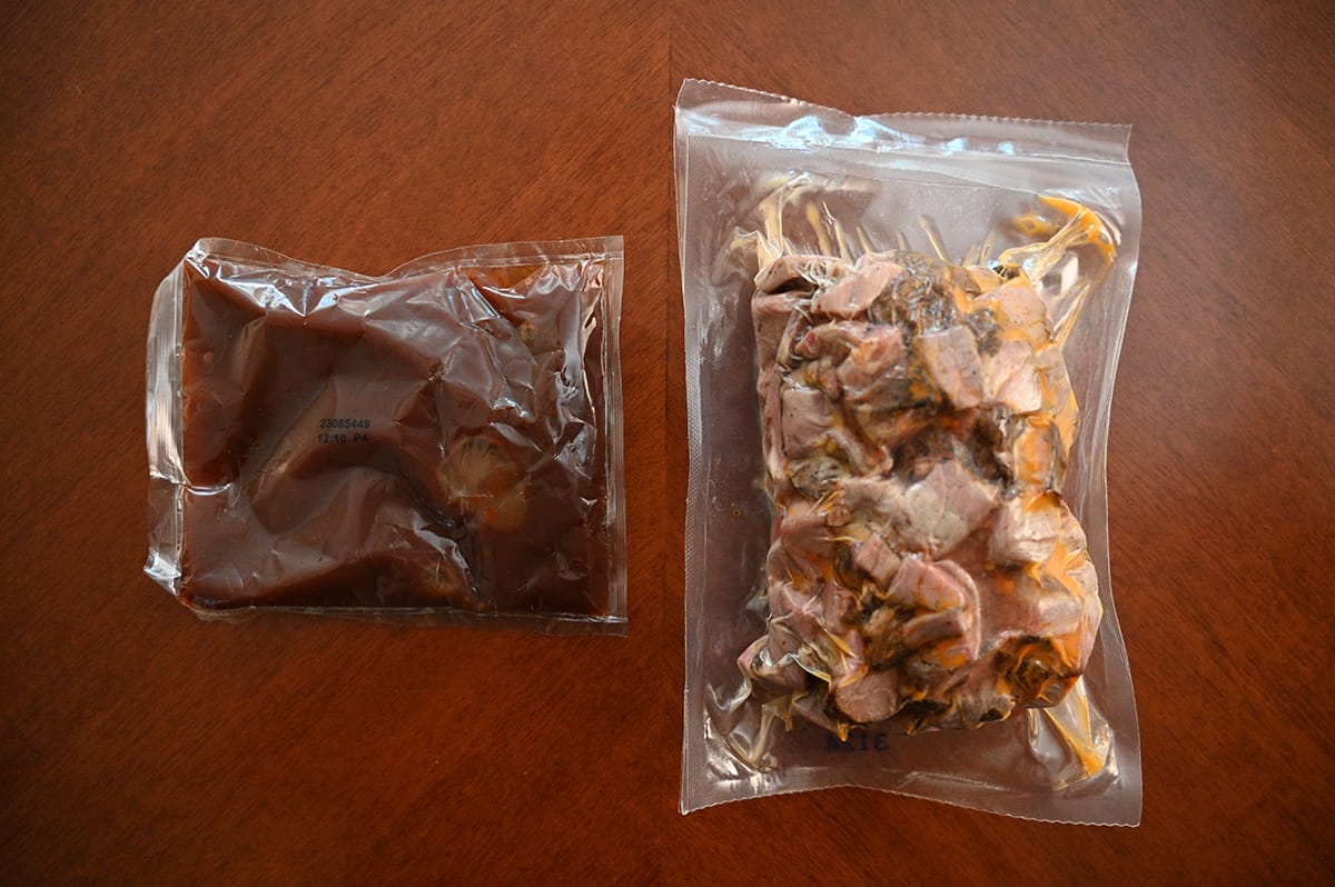 Top down image of a vacuum sealed bag of burnt ends beside a packet of sauce.