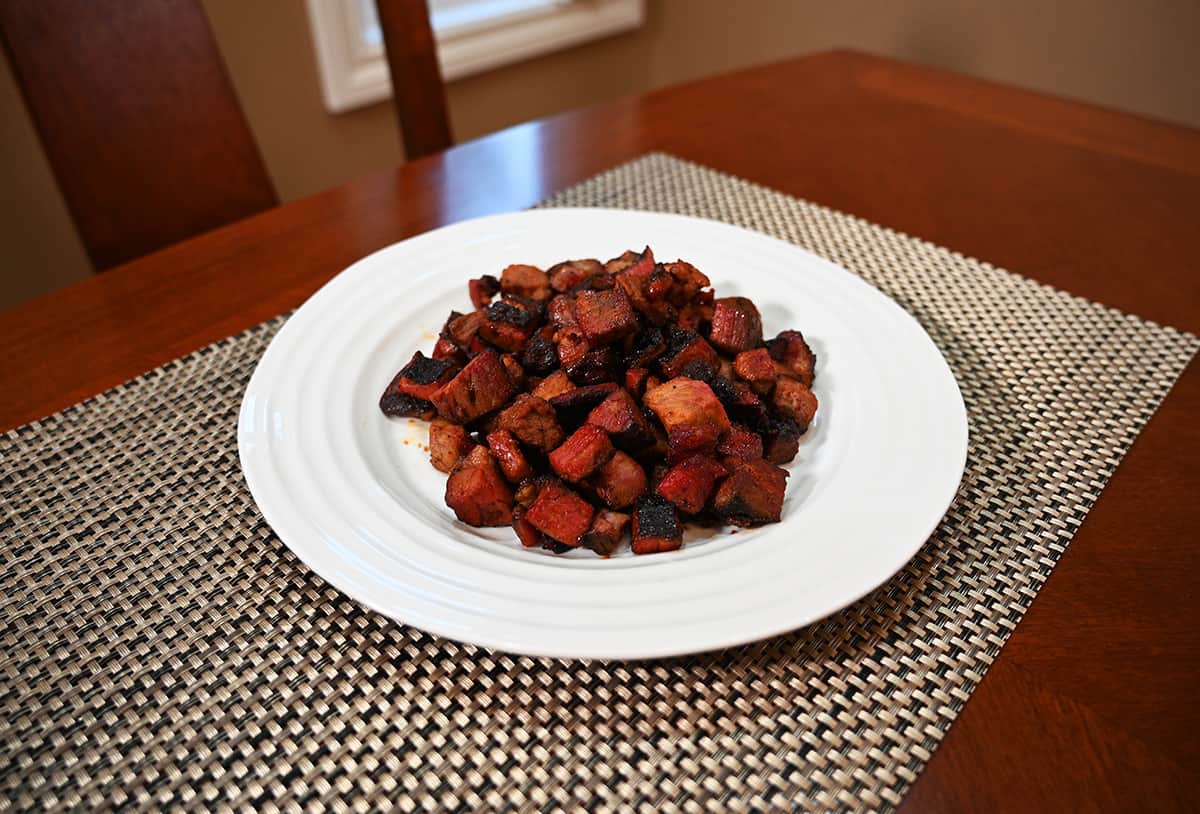 Side view image of a plate of cooked burnt ends on a table.