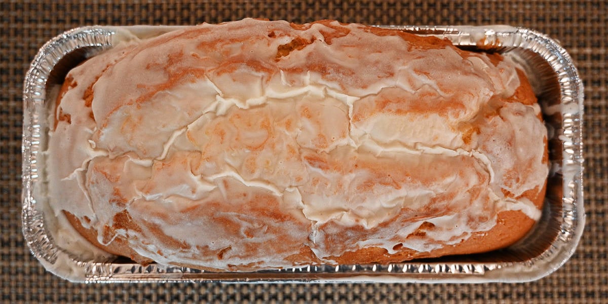 Top down image of an open container of the pound cake showing the top of the pound cake with the glaze on it.