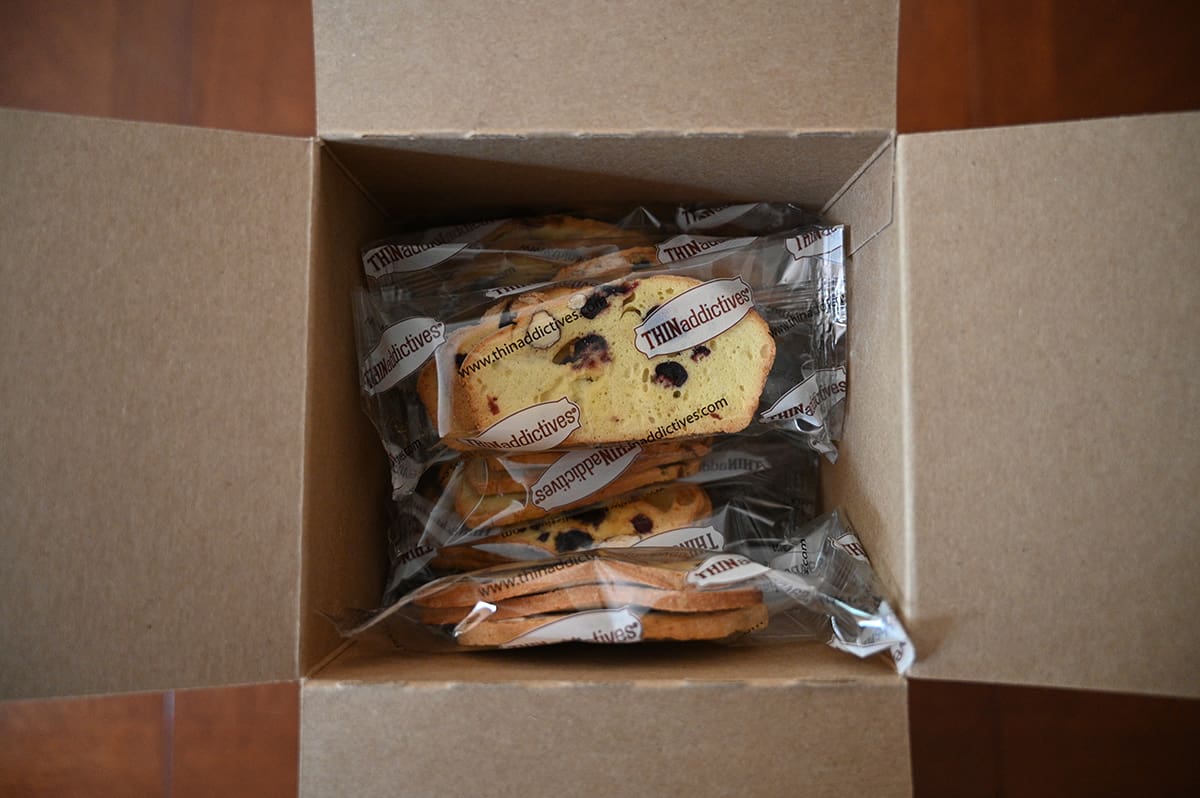 Top down image of an open box of Thinaddictives showing the packets of cookies.