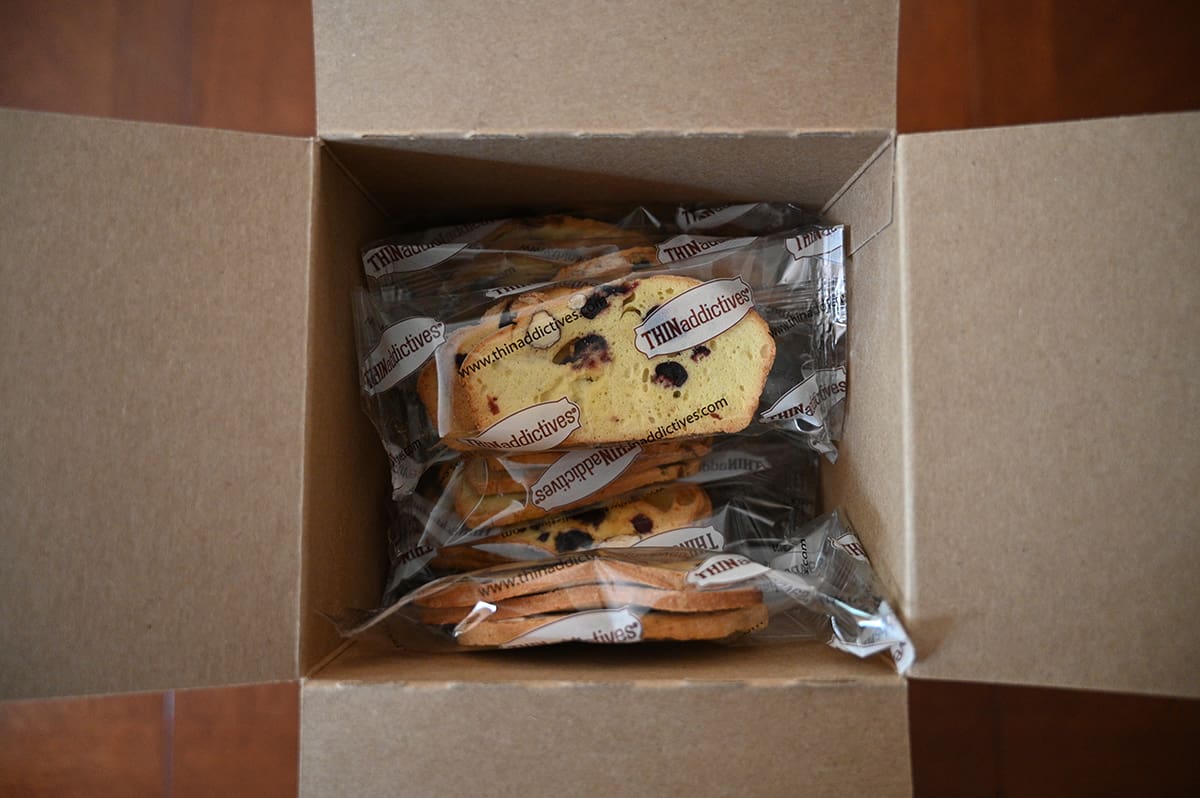 Top down image of an open box of Thinaddictives showing the packets of cookies.