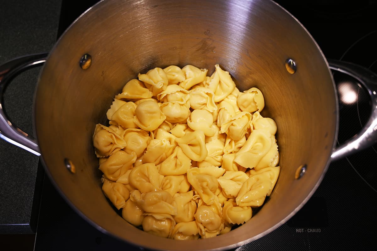 Top down image of the tortelloni cooked sitting in a big pot on the stovetop.