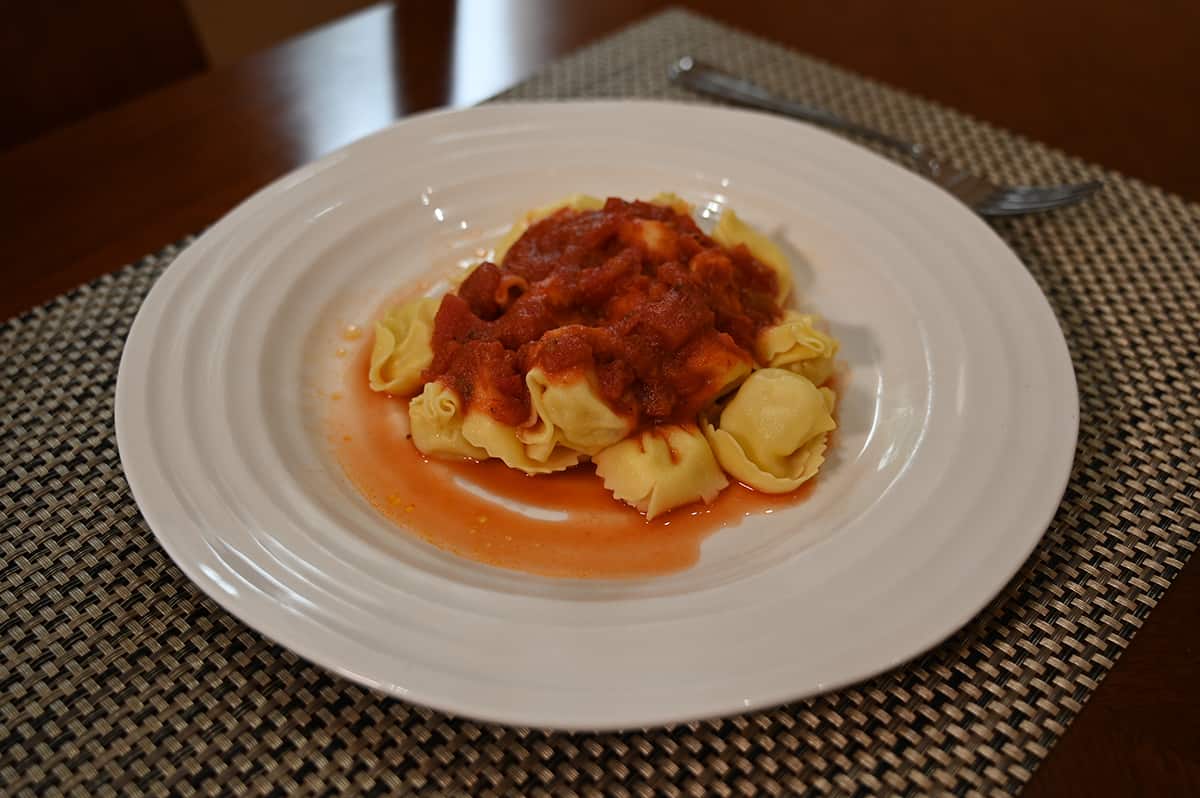 Top down image of the tortelloni cooked and prepared, served on a white plate with a red sauce.