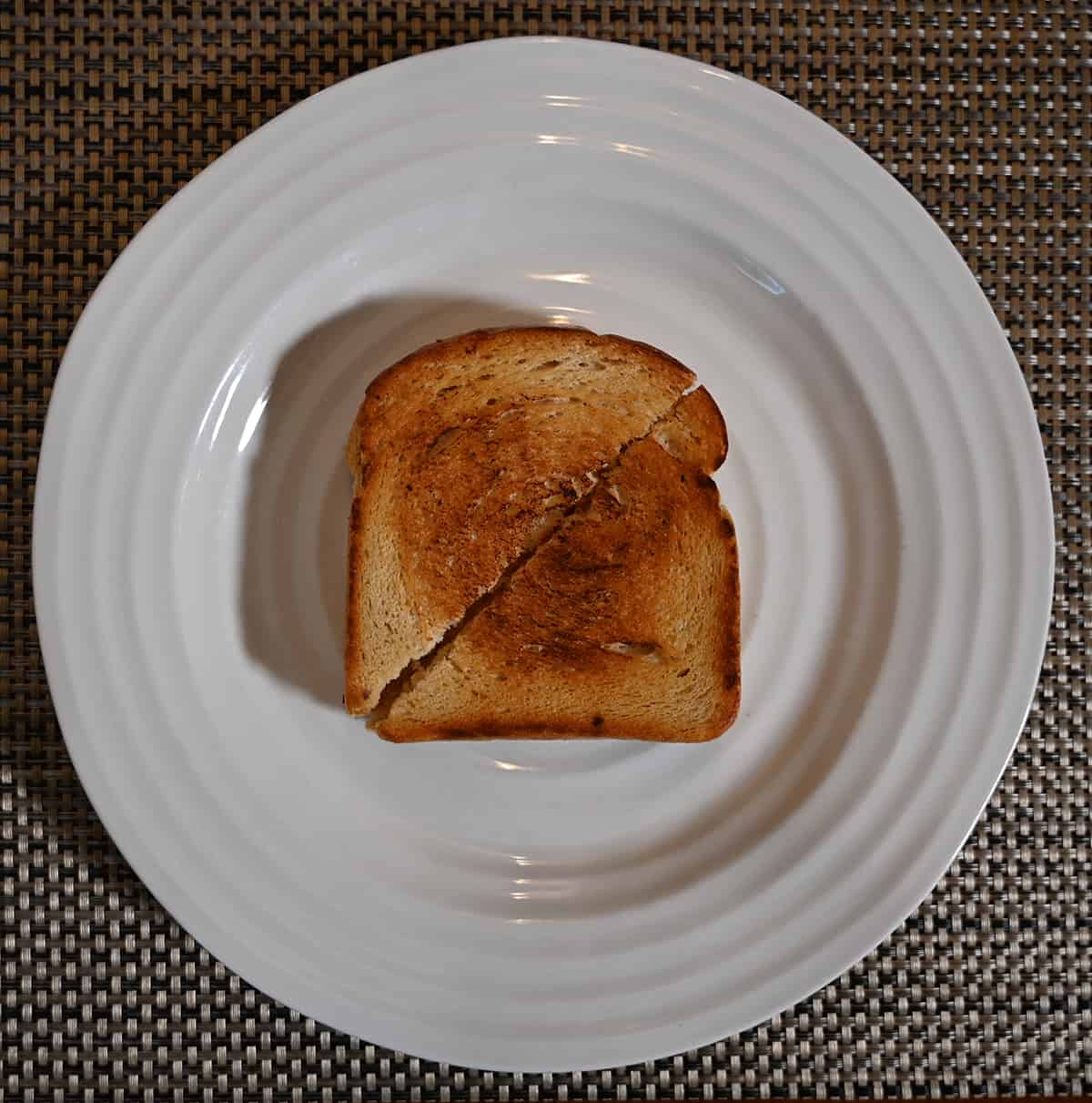 Top down image of a toasted grilled cheese cut in half and served on a white plate.