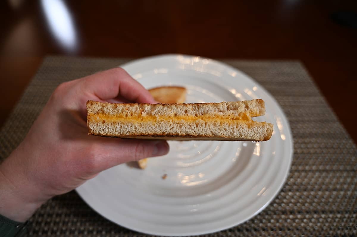Side view image of a grilled cheese sandwich that's been cut in half showing the cheese in the center.