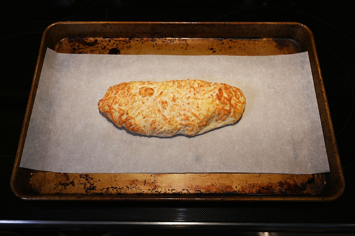 Image of one chicken bake unwrapped and sitting on a baking tray lined with parchment paper before baking in the oven.