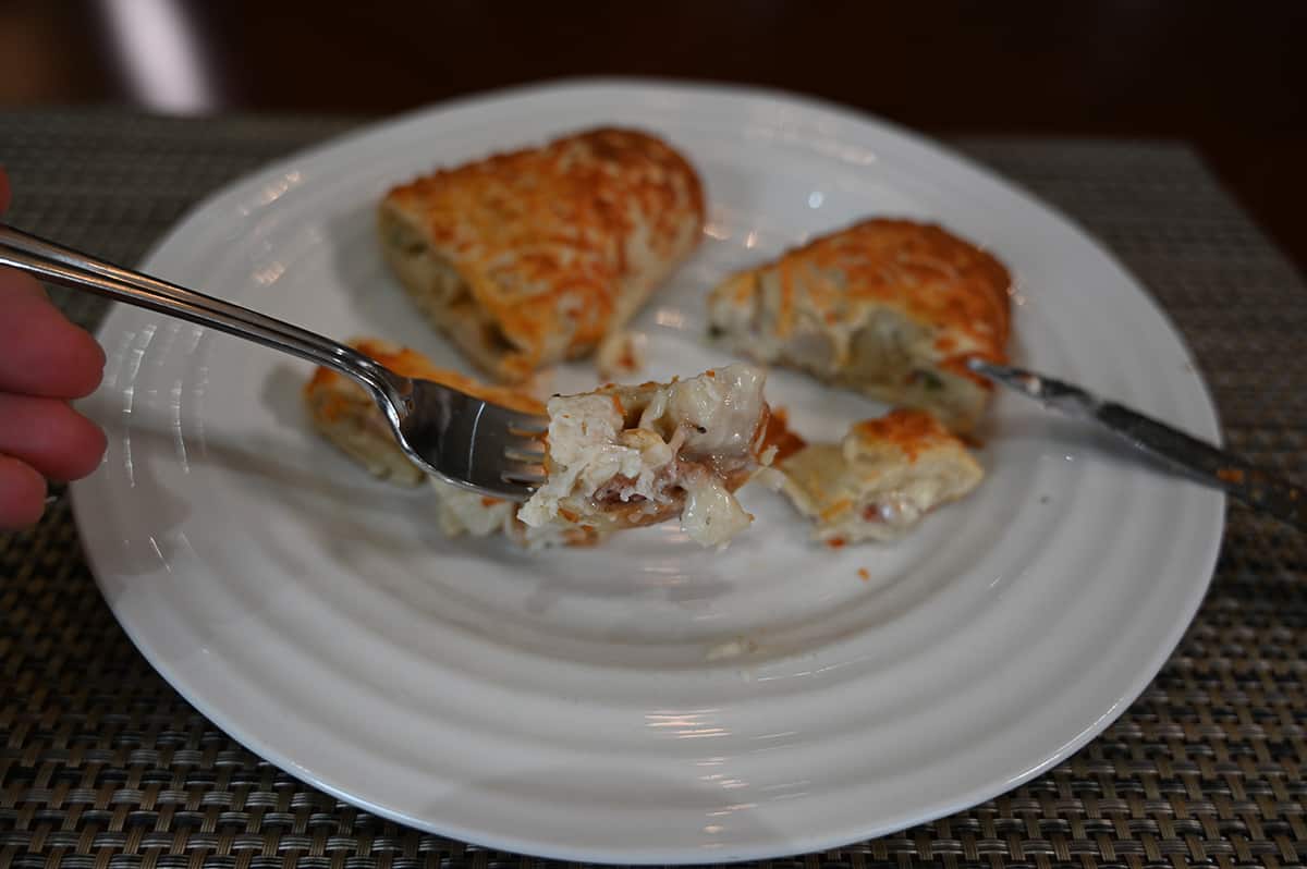 Top down image of a forkful of chicken bake hovering over a plate with the rest of the chicken bake served on it.