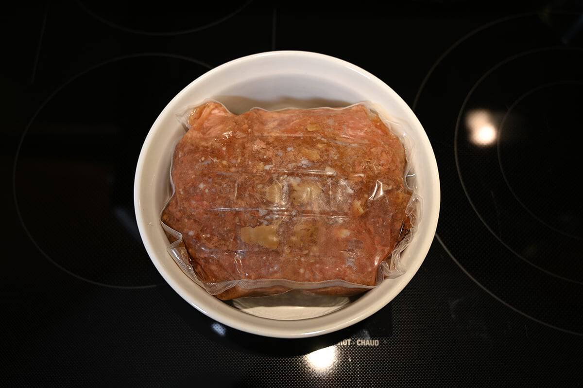 Image of the beef pot roast uncooked in the bag it comes in sitting in a microwave safe dish.