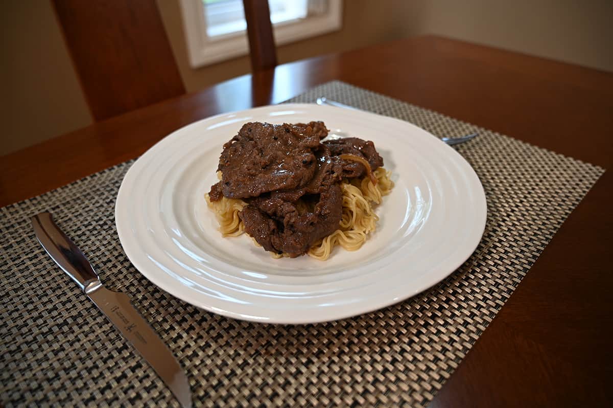 Side view image of a plate of cooked beef bulgogi served on top of some noodles.