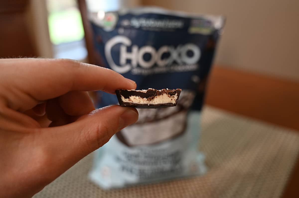 Closeup image of a hand holding one coconut cup with a bite taken out of it.