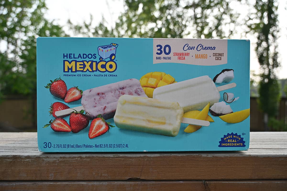 Image of the Costco Helados Mexico Ice Cream Bars box sitting on a deck outside with trees in the background.