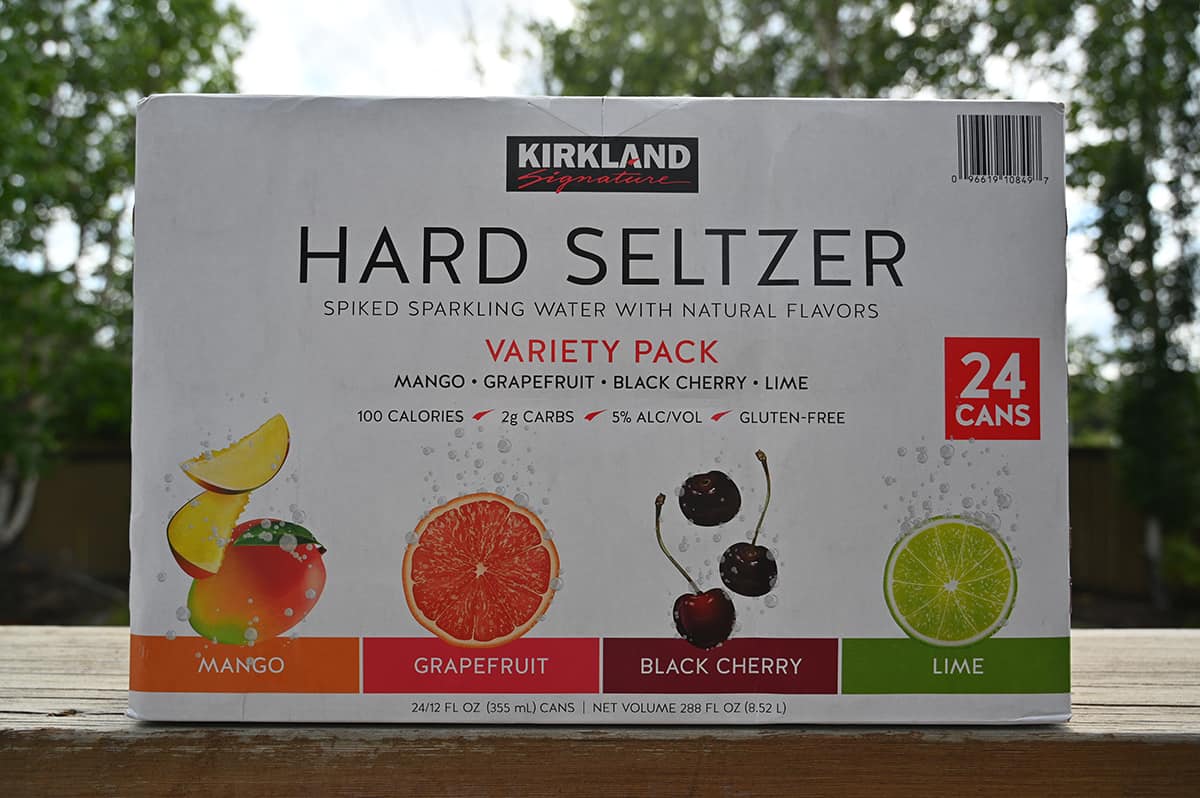 Costco Kirkland Signature Hard Seltzer box sitting on a deck outside with trees in the background. 