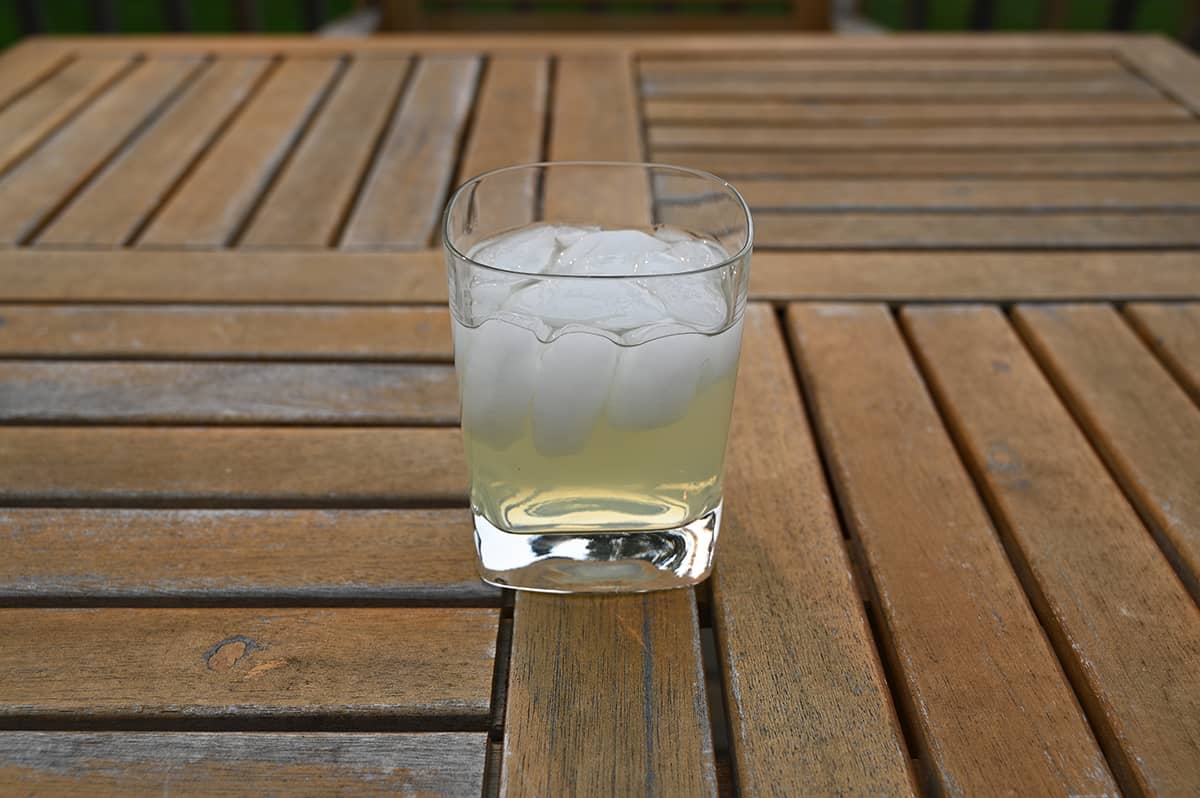 Image of one poured glass of golden margarita wine cocktail sitting on a table outside.