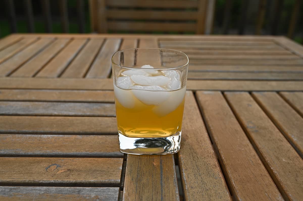 Image of one poured glass of peach margarita wine cocktail sitting on a table outside.