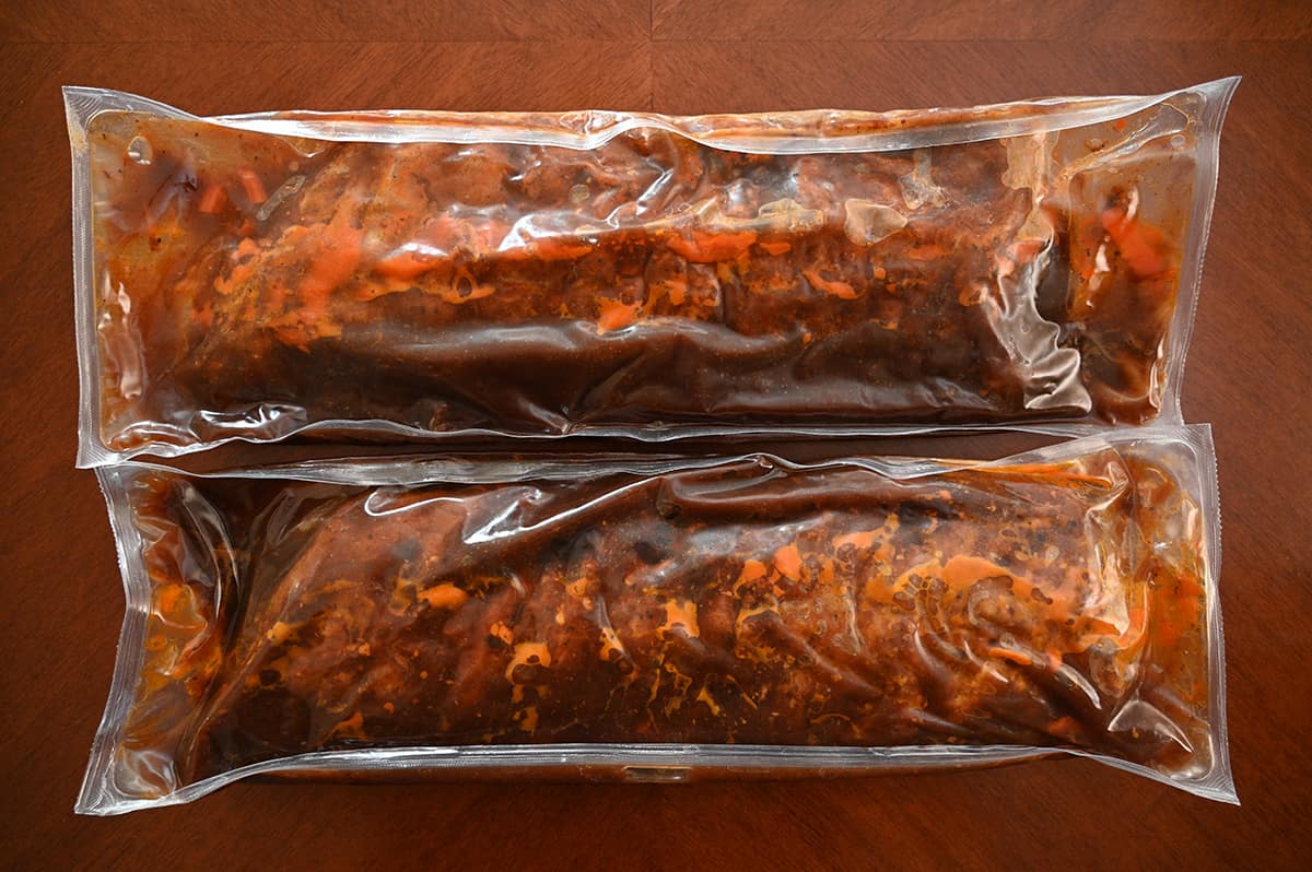 Top down image of the uncooked ribs out of the box in their vacuume-sealed packaging, sitting on a table.