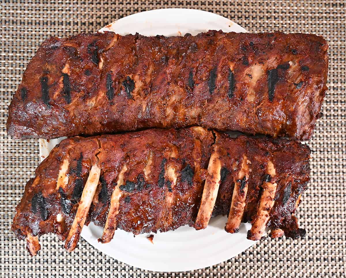 Top down image of two slabs of ribs grilled and served on a white plate.