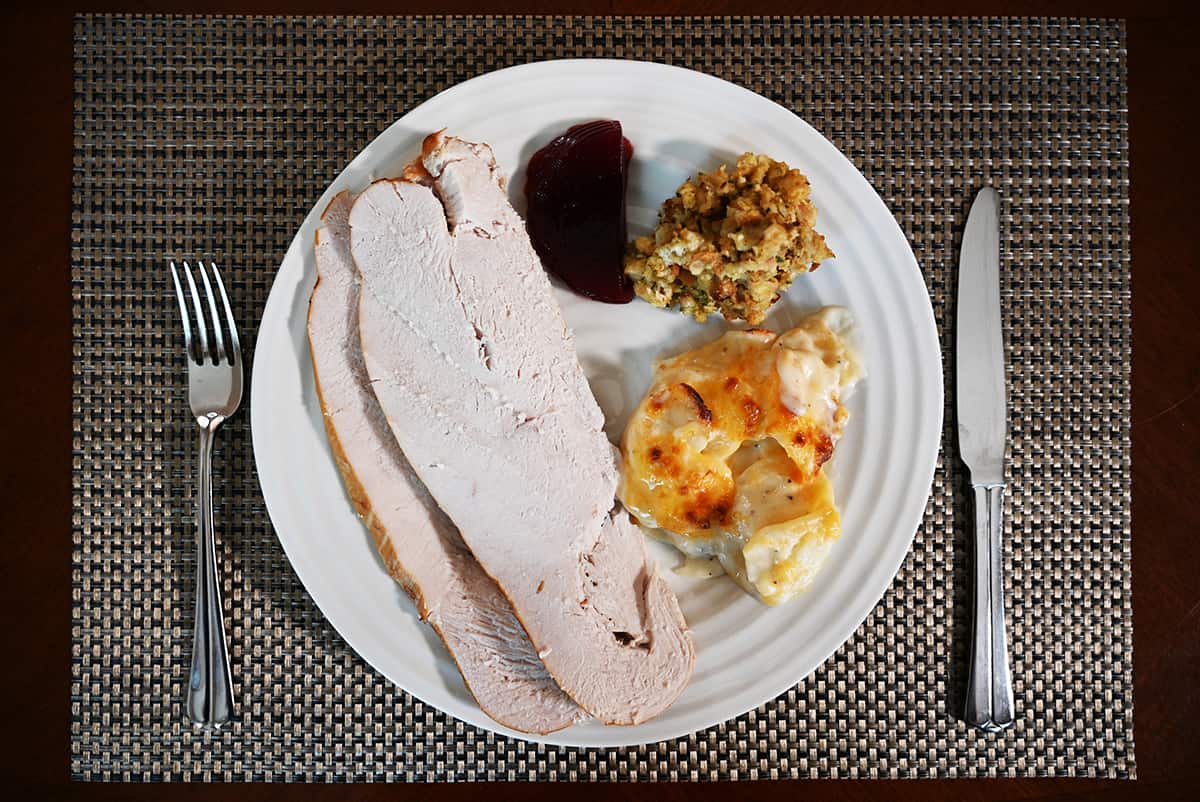 Top down image of a plate with turkey, scalloped potatoes, cranberry sauce and stuffing on it.