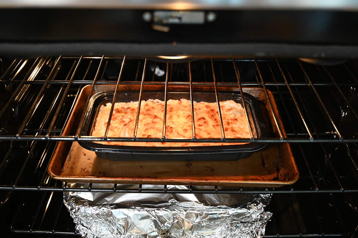 Side view image of a tray of scalloped potatoes being baked inside an oven on the middle rack.