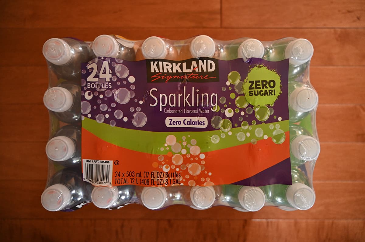 Top down image of the case of Kirkland Signature Bottled Carbonated Flavored Water sitting on a hardwood floor.