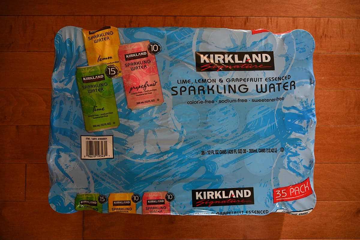 Top down image of the case of Kirkland Signature Essenced Sparkling Water sitting on a hardwood floor.
