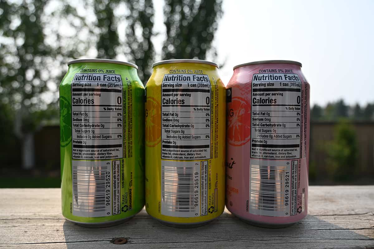 Image showing tthe back nutrition facts of three different flavors of cans of sparkling water sitting on a  deck.