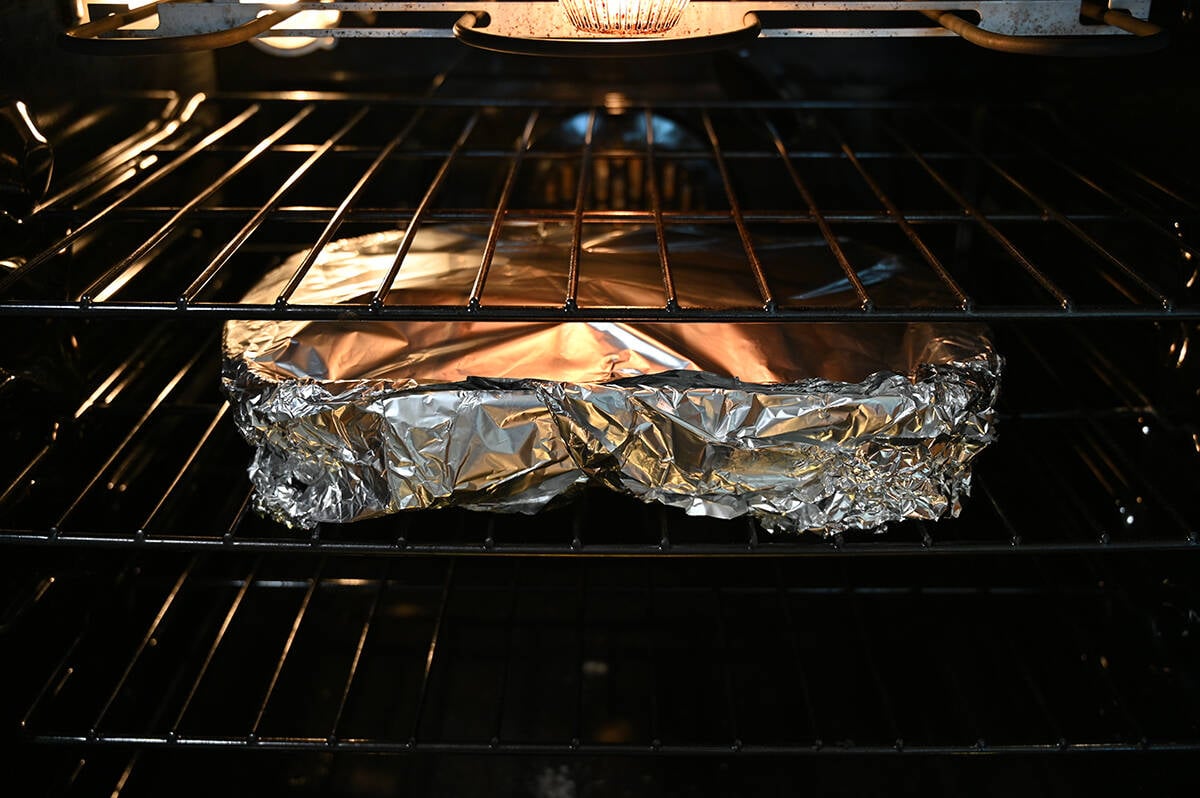 Image of a pan covered with aluminum foil sitting on the middle rack in the oven.