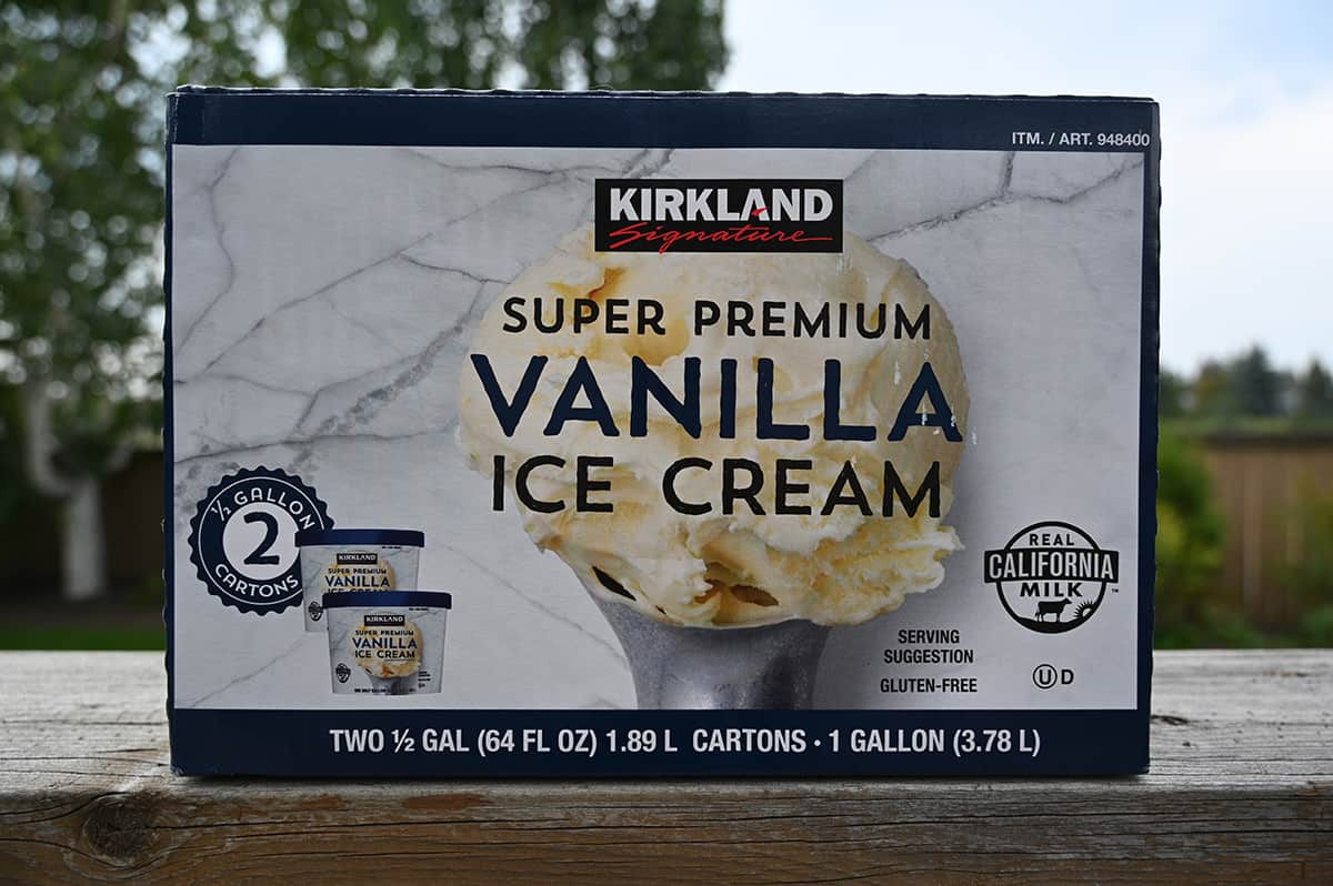 Costco Kirkland Signature Super Premium Vanilla Ice Cream box sitting on a deck outside with trees in the background.