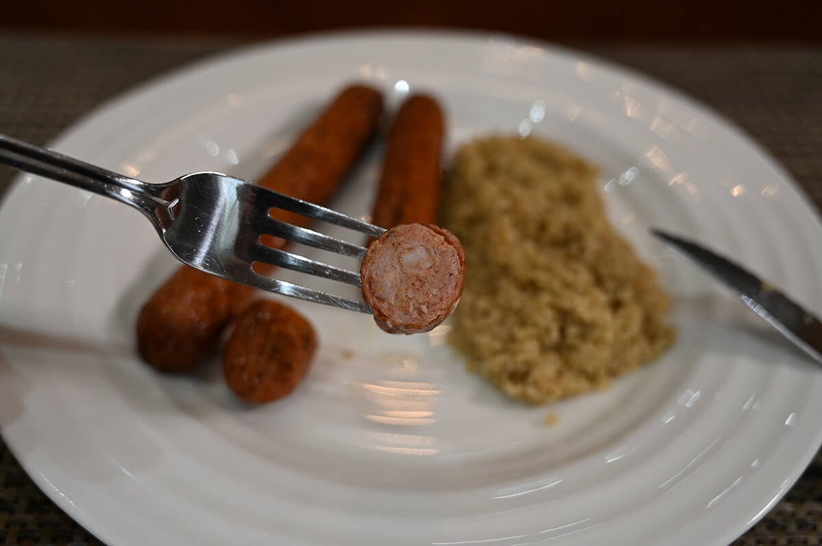 Closeup side view image of an andouille sausage piece on a fork cut so you can see the center of the sausage.