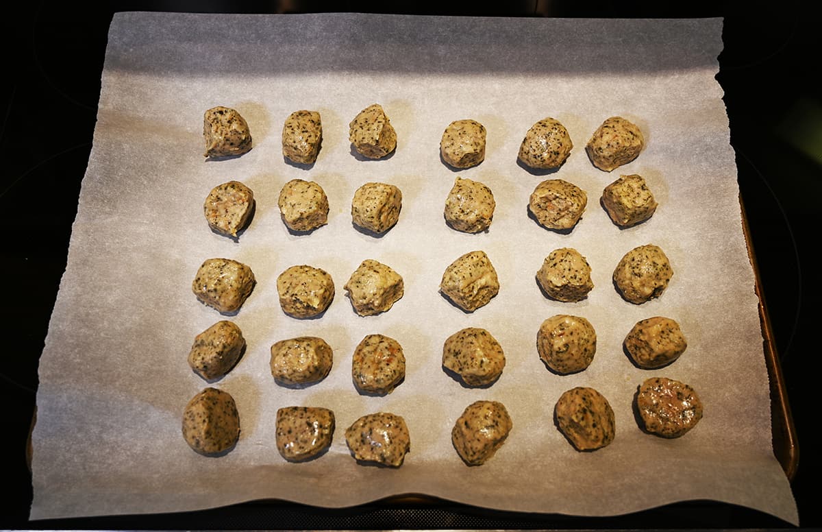 Top down image of a tray of 30 meatballs prior to baking them.