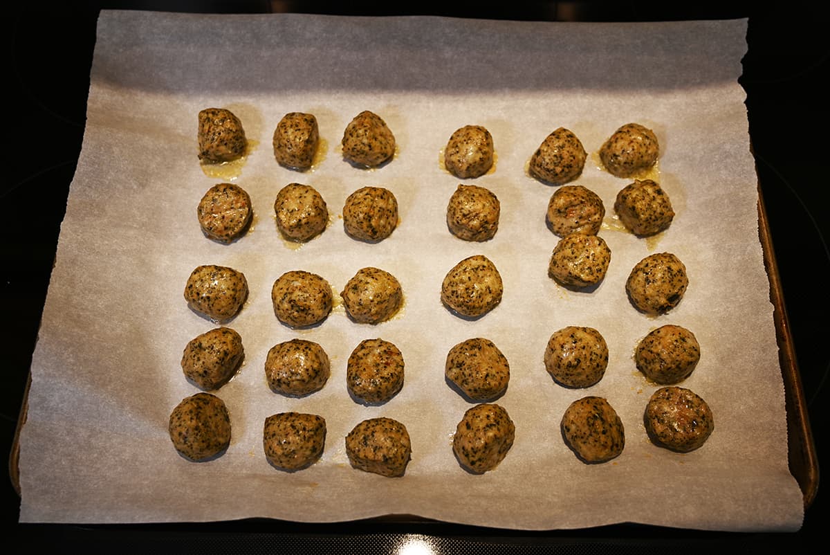 Top down image of a tray of 30 meatballs out of the oven after being baked.