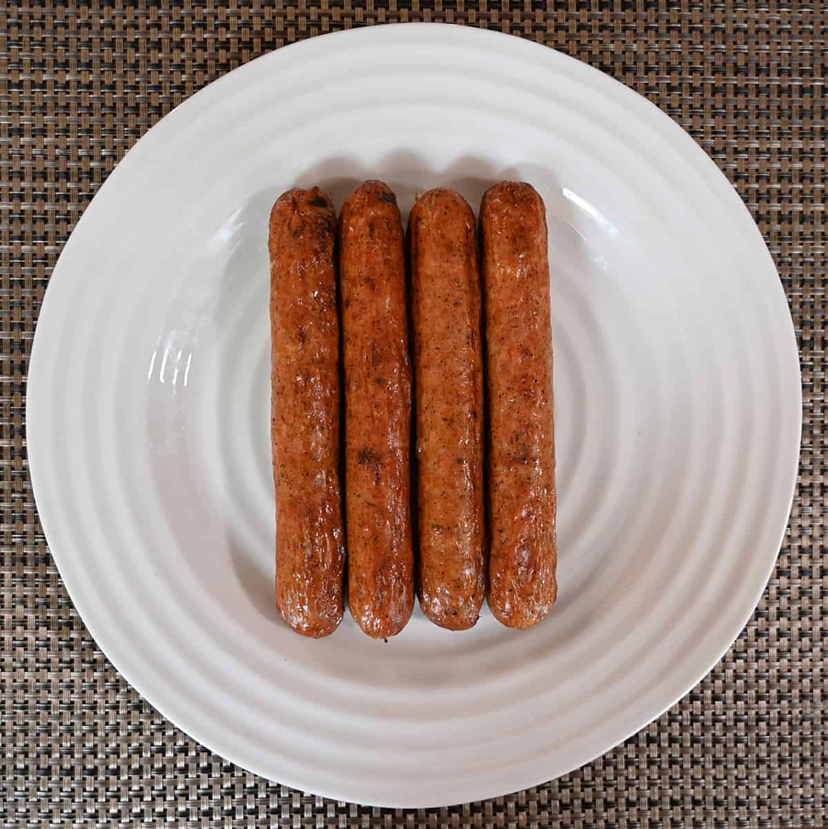 Top down image of four cooked andouille sausages served on a white plate.